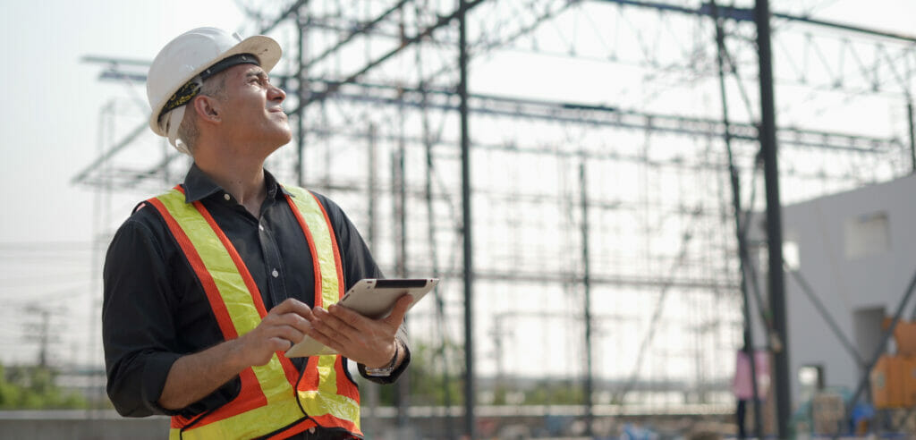 A contractor looks at their jobsite while holding a tablet. STACK's daily reports help improve field productivity.