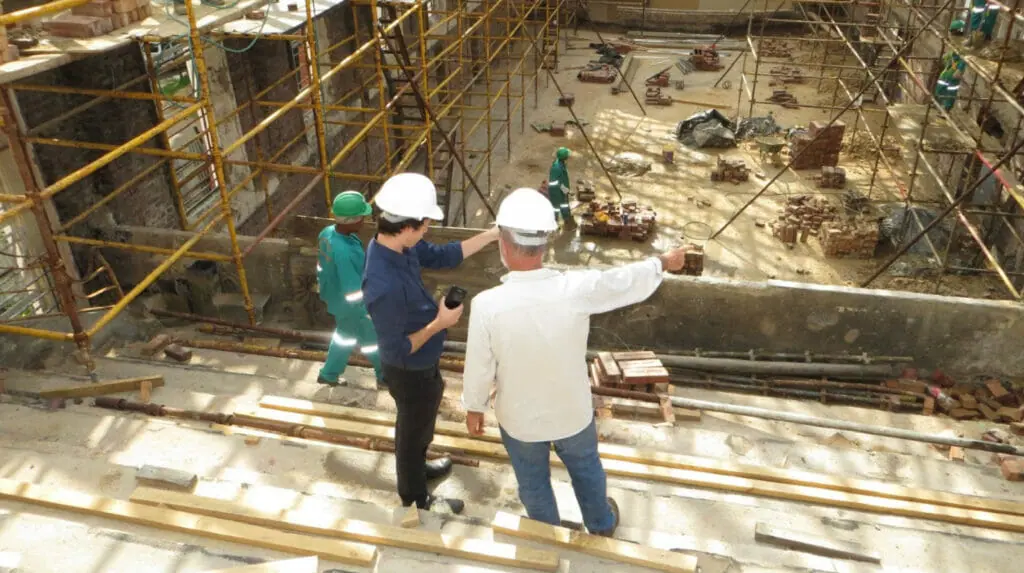 Two construction workers look out at their construction site.