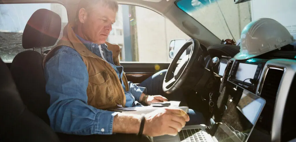 A contractor works from his laptop in his truck.