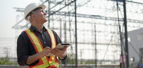 A contractor looks at their jobsite while holding a tablet. STACK's daily reports help improve field productivity.
