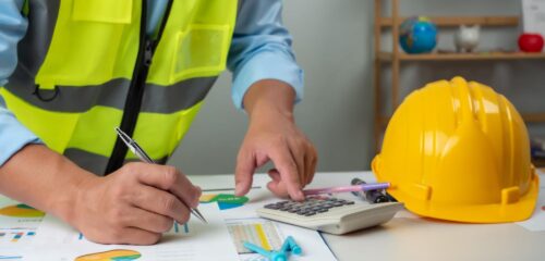 una persona que teclea en una calculadora y examina distintos planos de construcción